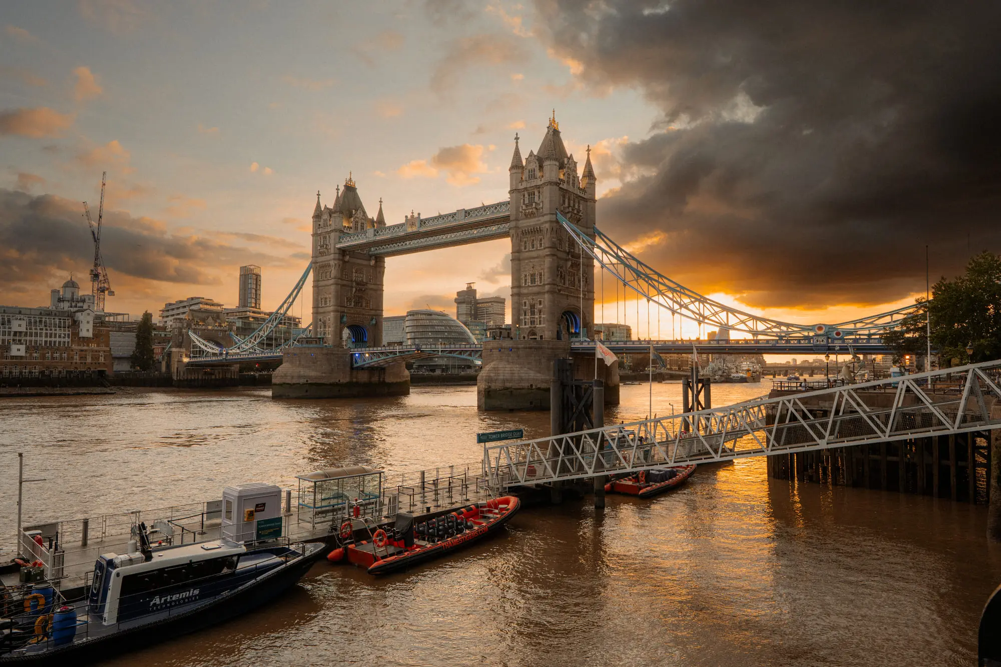 Tower Bridge under a fiery sunset, police boats moored on the Thames