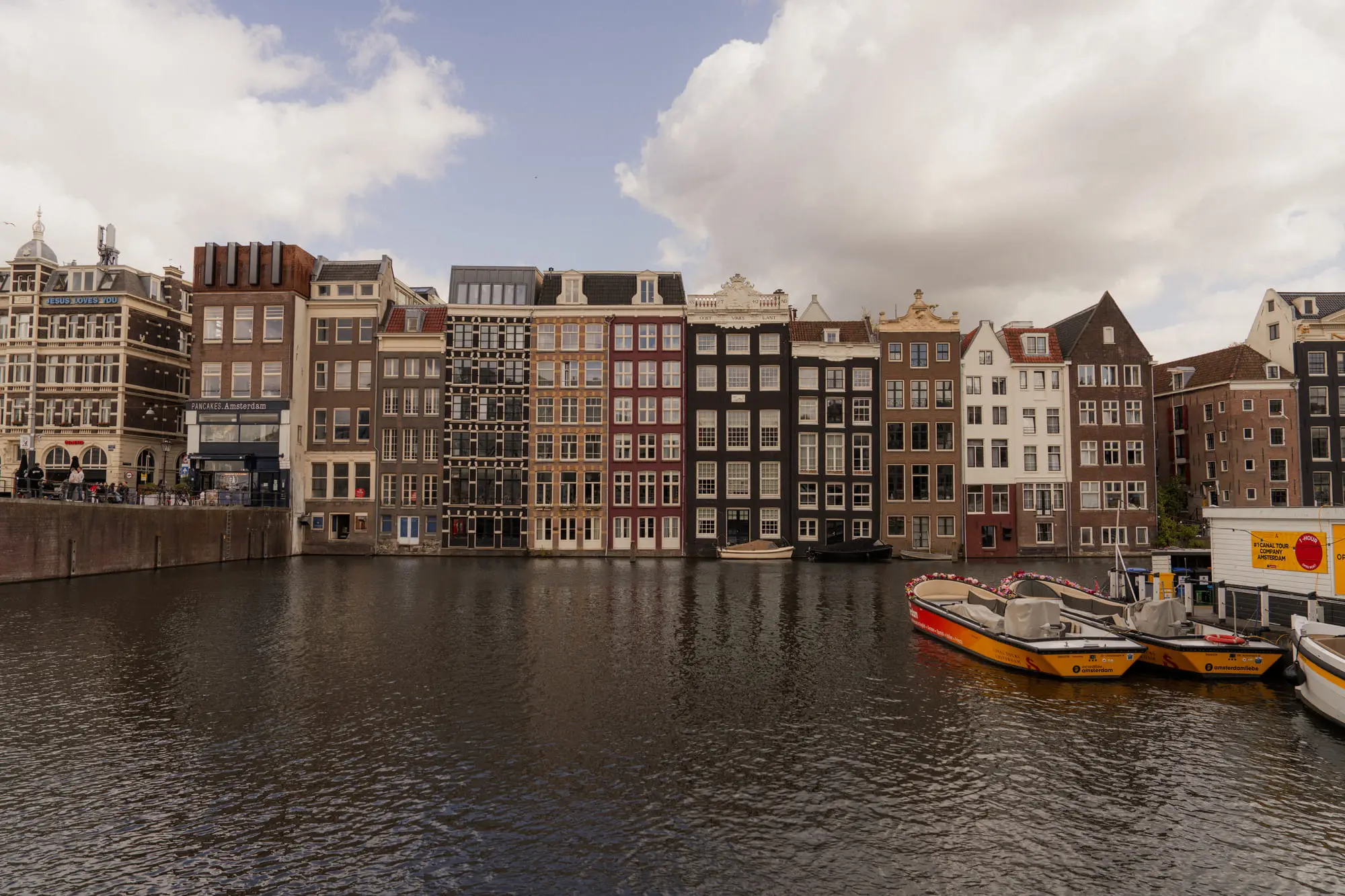 The dancing houses of the Damrak, tour boats below a cloudy sky