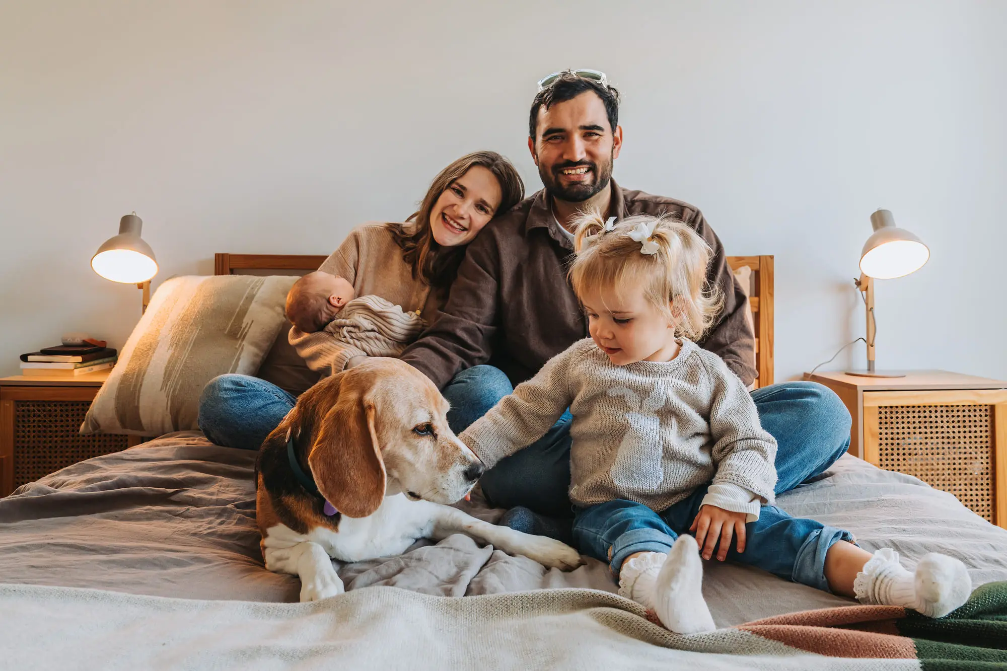 A family and their beagle on the bed, everyone smiling
