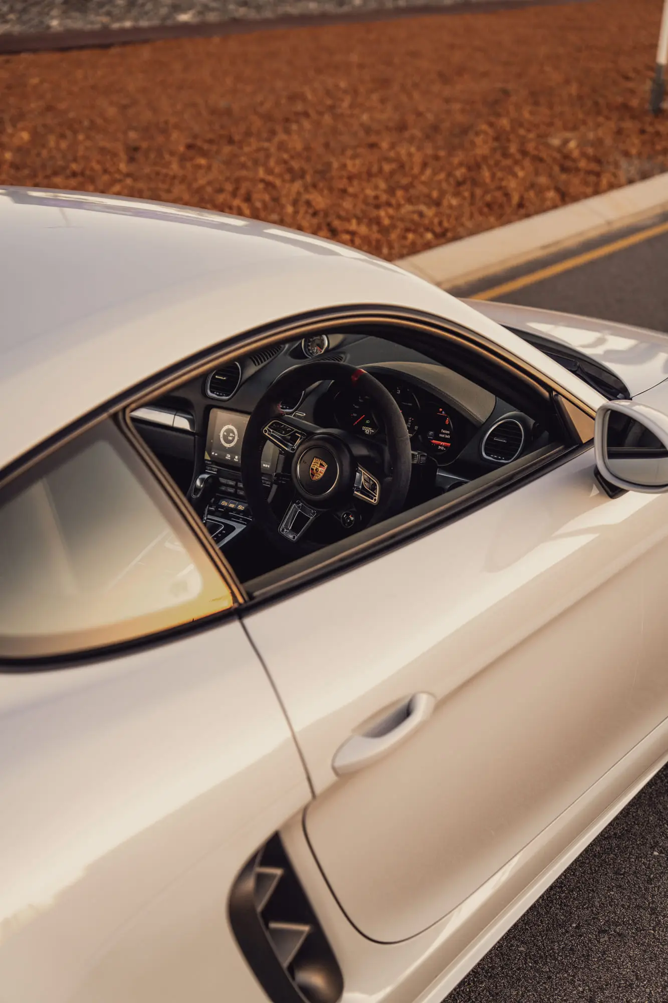 The steering wheel through the side window, sunset in the glass