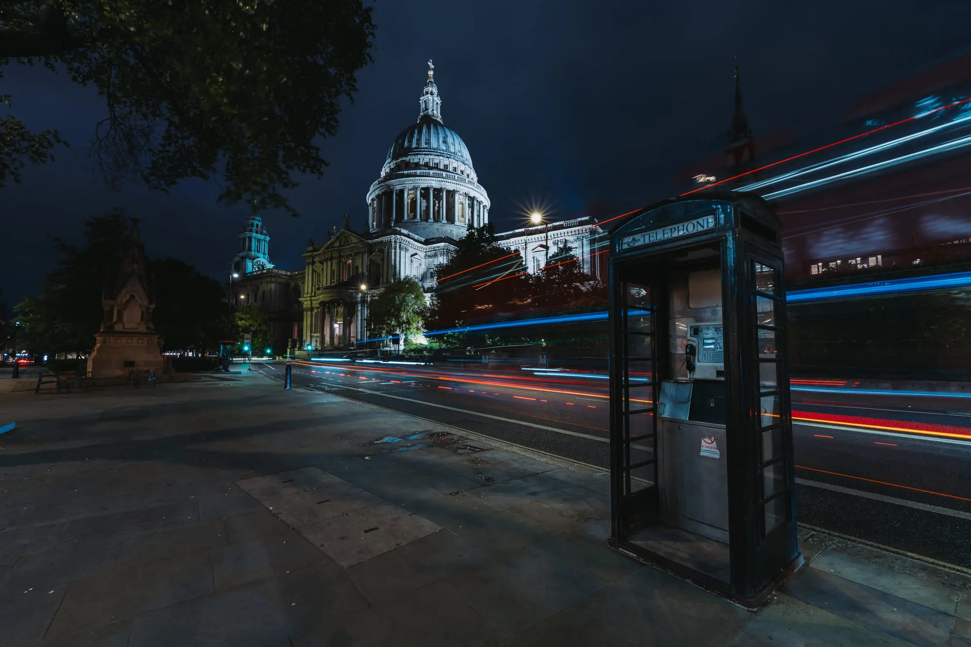 St Paul's Cathedral at night behind streaks of traffic light and a black phone box
