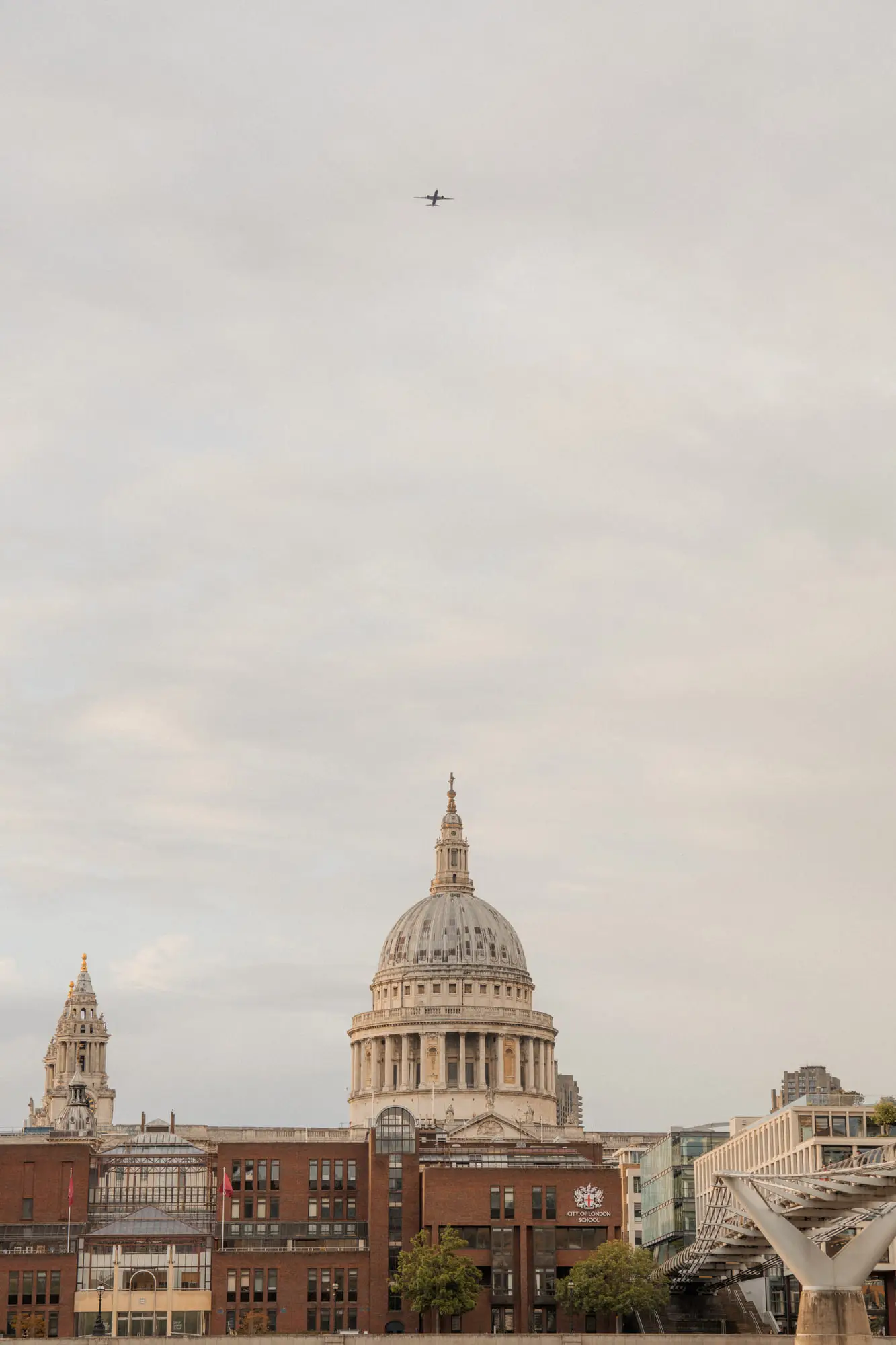 St Paul's dome above the rooftops, a plane crossing the sky