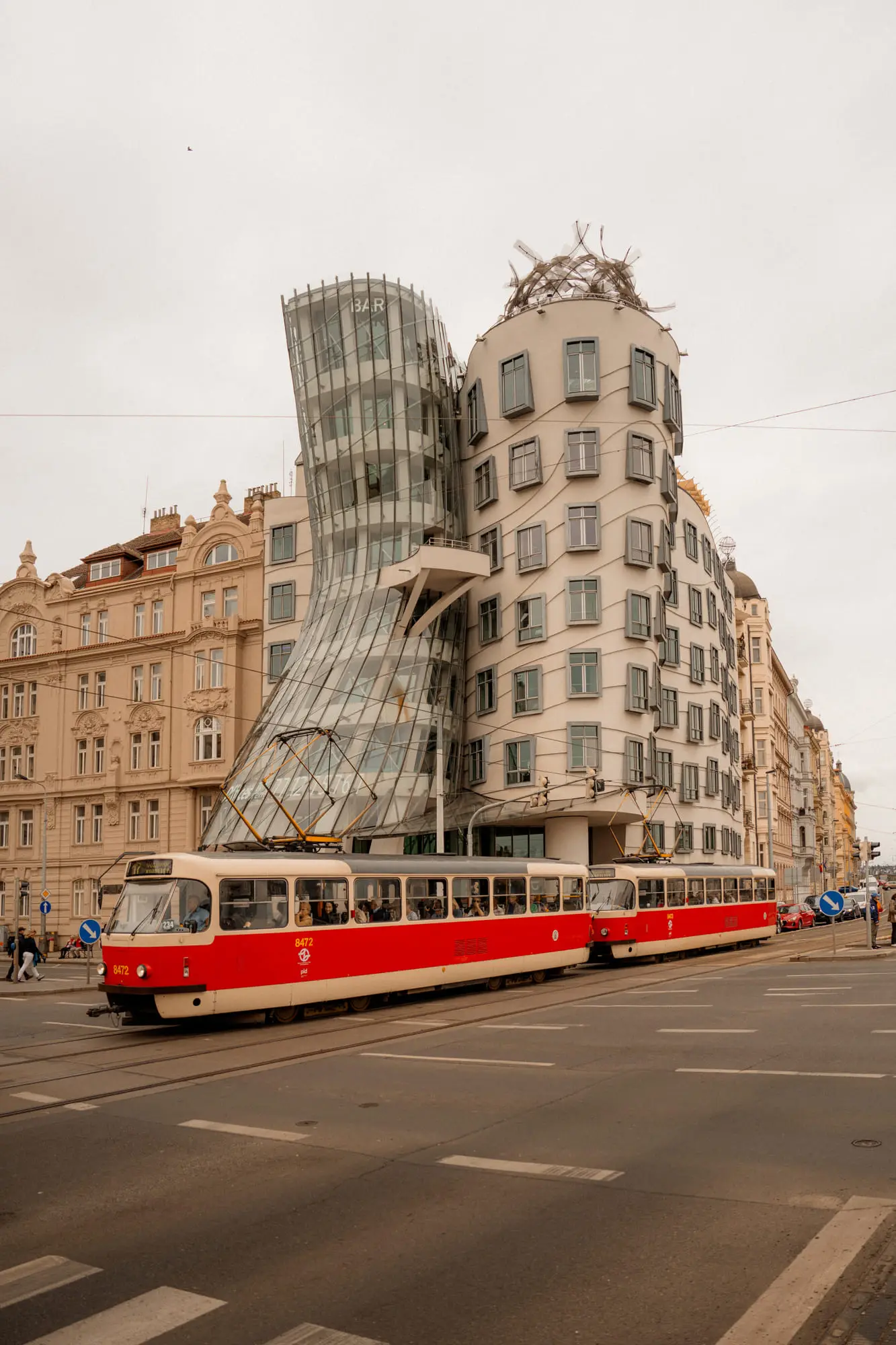 A red tram passing the Dancing House, Prague