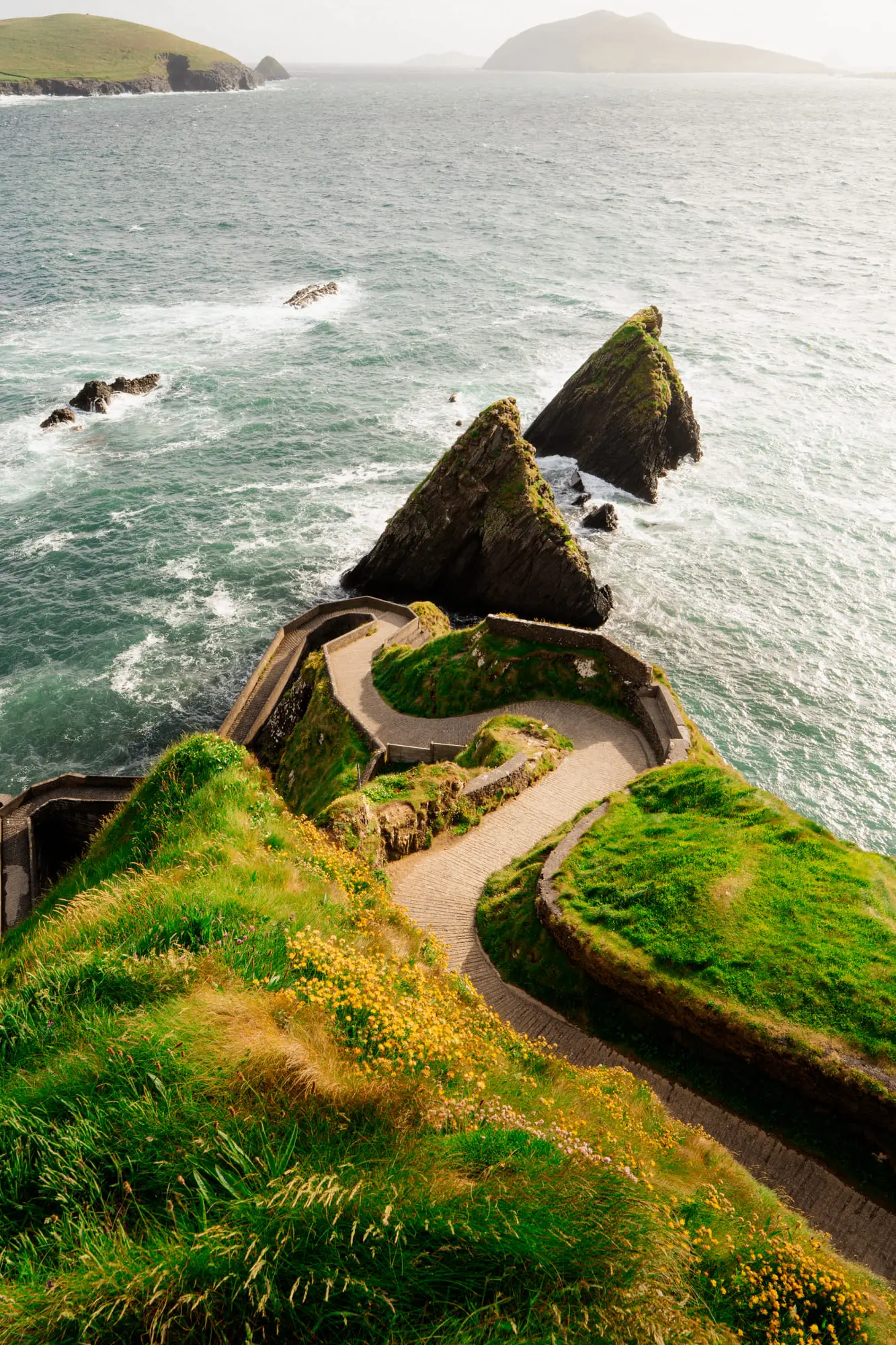 The path to Dunquin Pier winding between sea stacks, backlit