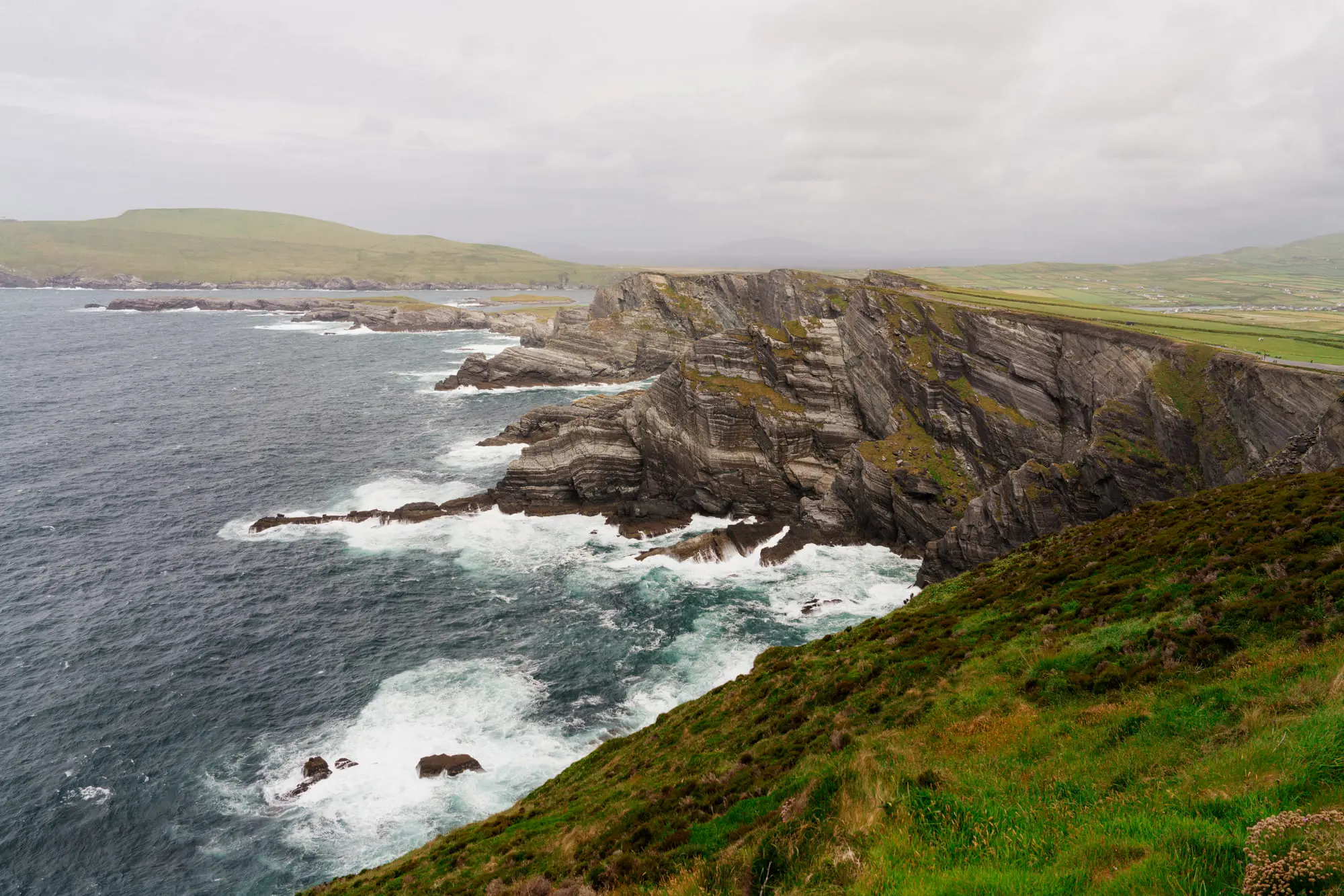 The Kerry Cliffs under a grey sky, surf breaking below