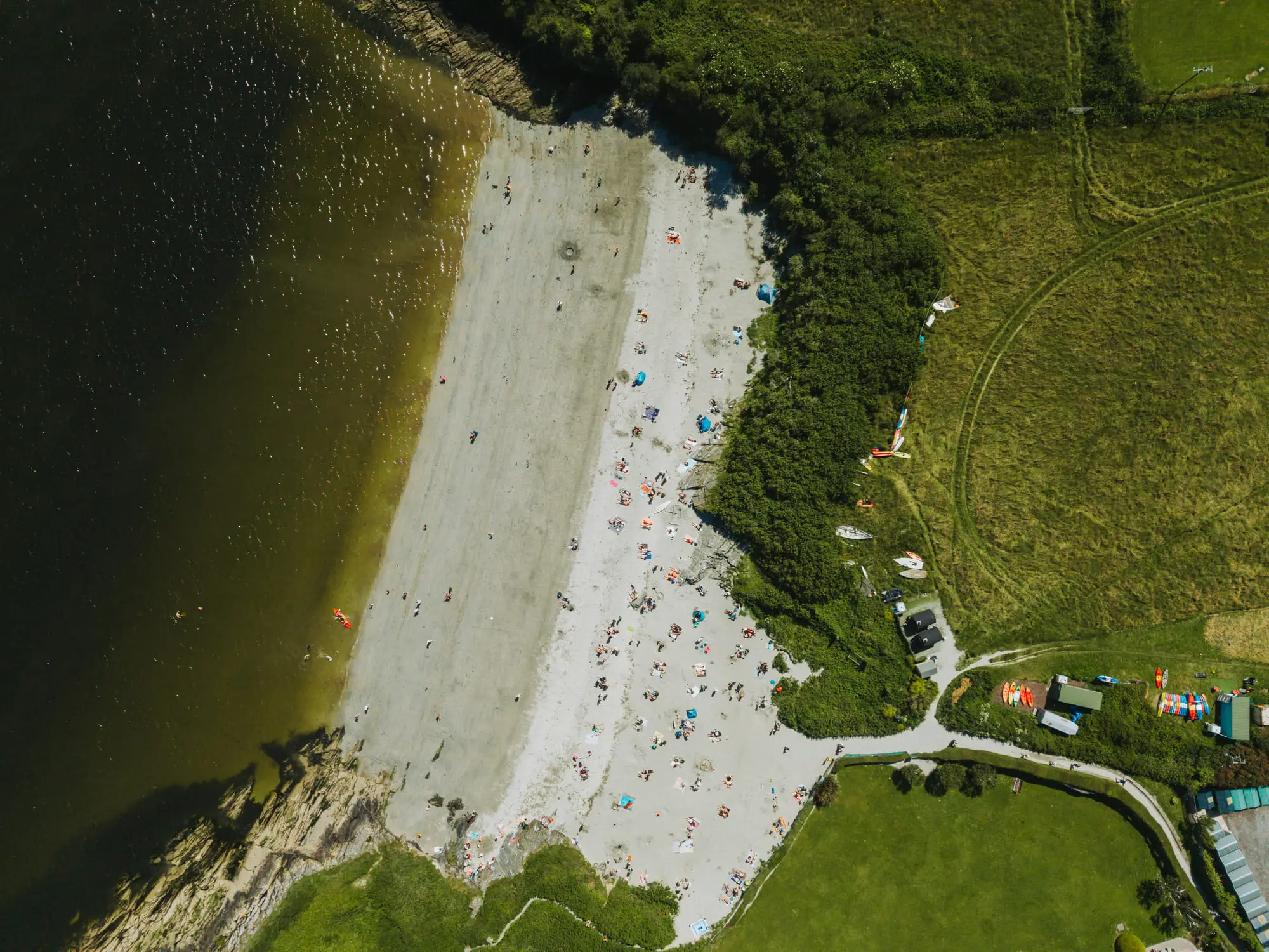 A crowded river-mouth beach, straight down from above